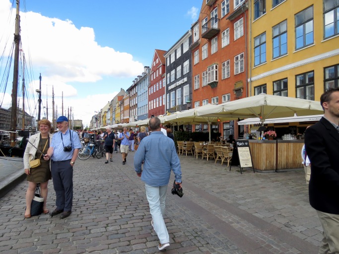 Tourists stop for selfies and locals casually stroll past colorful shops along the Nyhavn Canal in Copenhagen, Denmark - Read about the sites and activities in Copenhagen at www.beautifulfillment.com