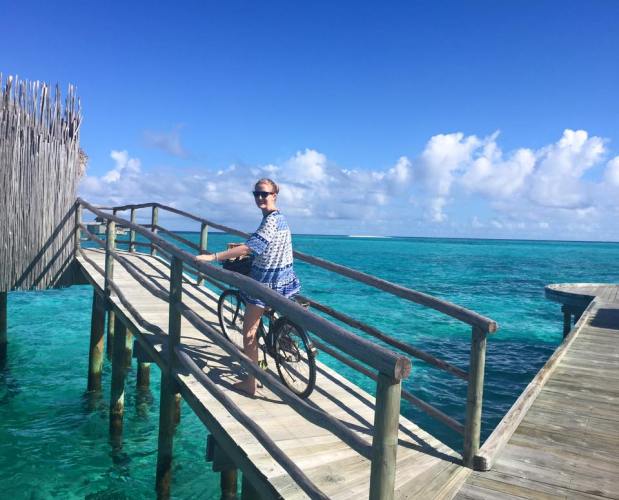 Sally riding her personalised bike to her overwater villa in The Maldives - MissMaps.com Featured Female Traveler